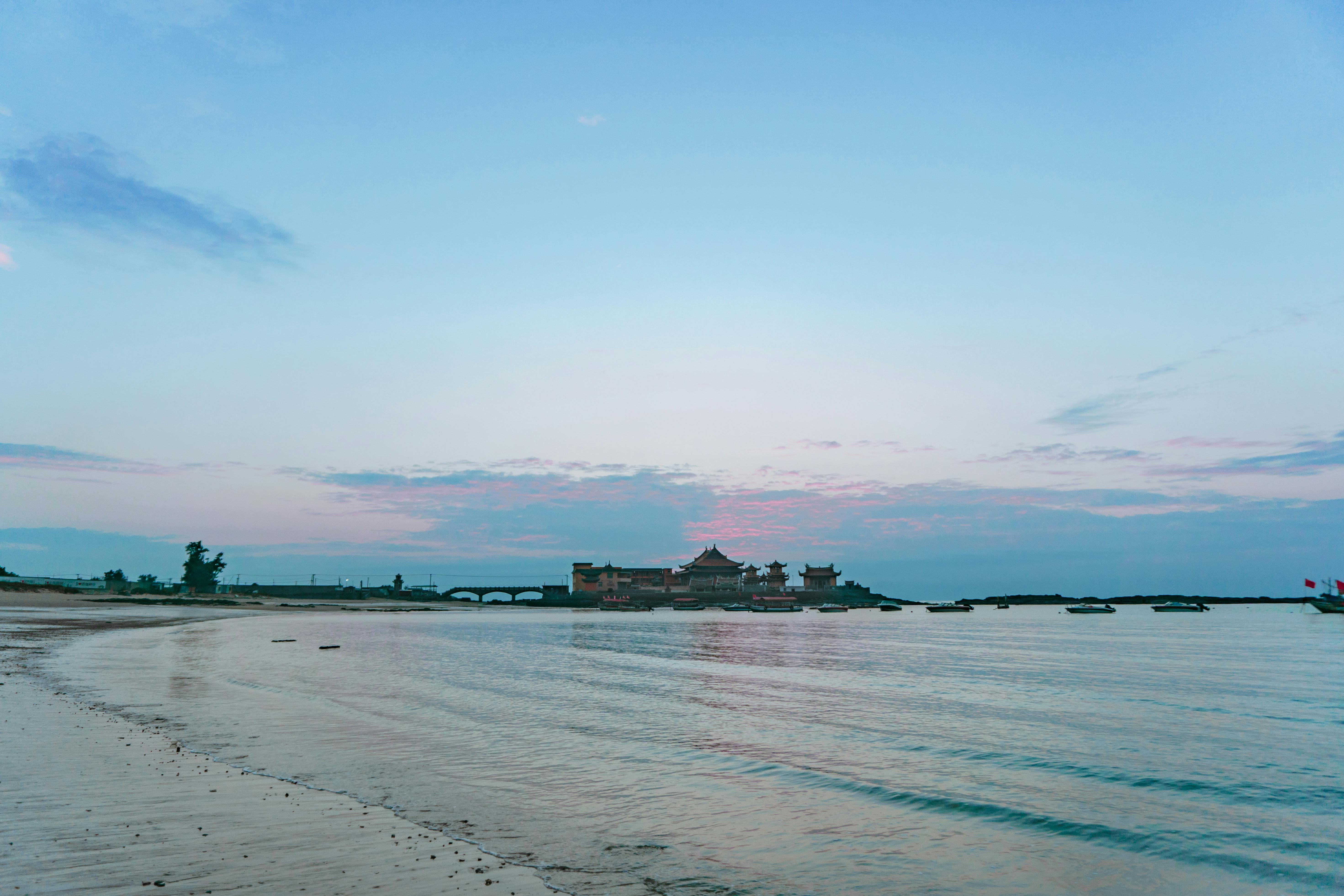 日出时分，宁静的海岸、平静的水域和遥远的海岸线构成了一幅美景