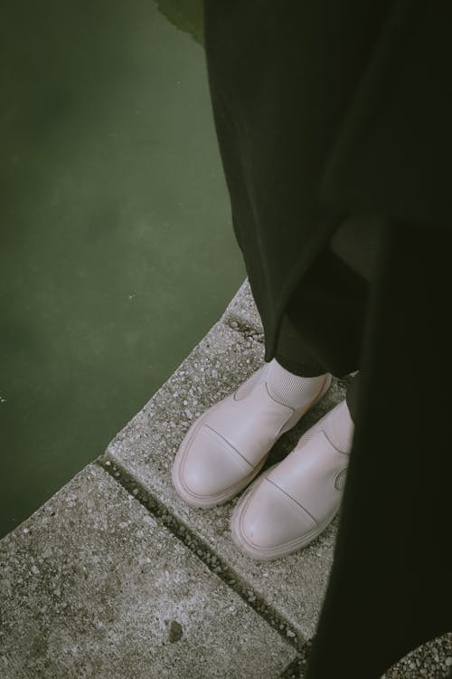 Shoes of Person Standing near Water