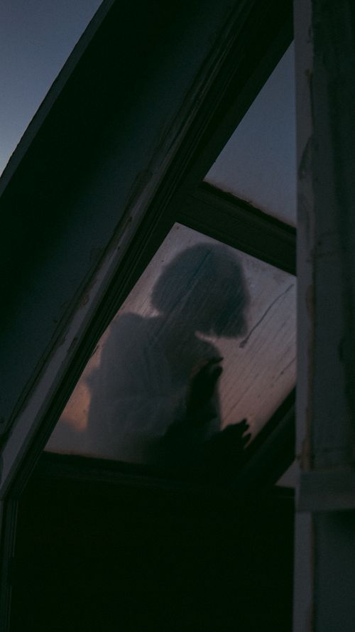 Free Mysterious silhouette of a woman seen through a foggy, back-lit window, evoking a haunting mood. Stock Photo