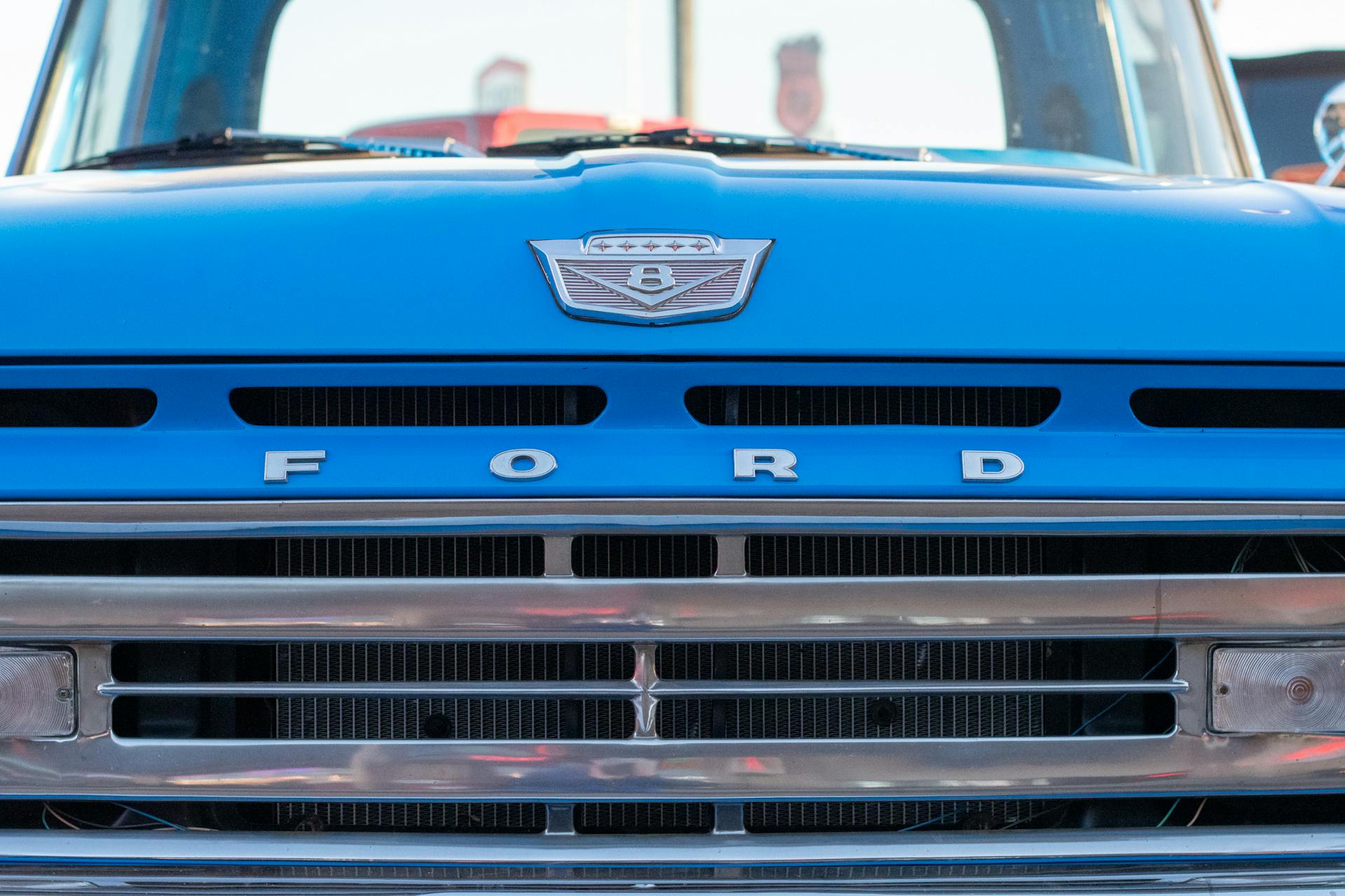 Detailed close-up of a blue vintage Ford truck grille with emblem, capturing classic automobile design.