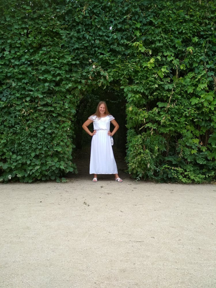 Woman In A White Dress Standing In The Garden Gate 