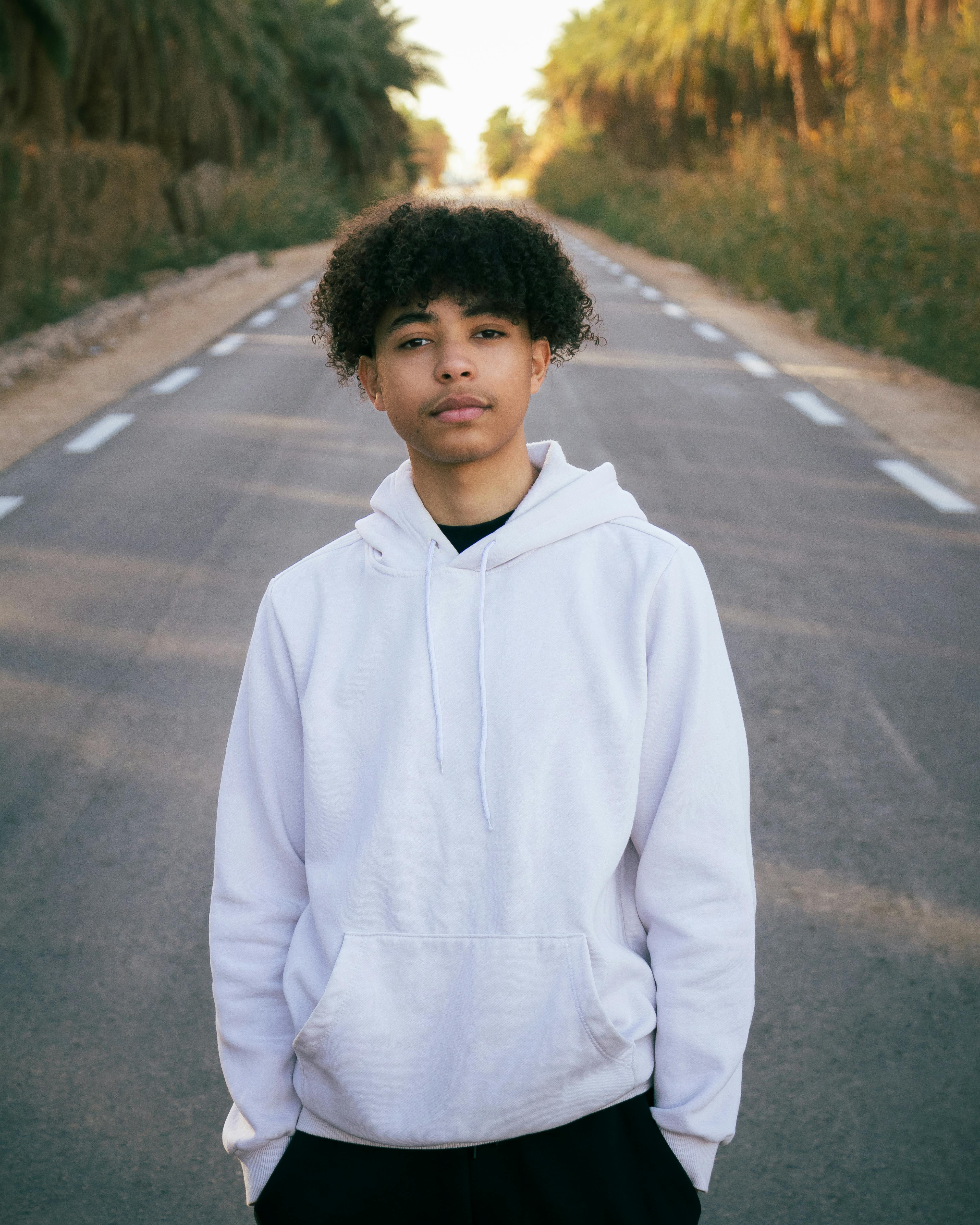Man in White Hoodie Standing on Road Free Stock Photo