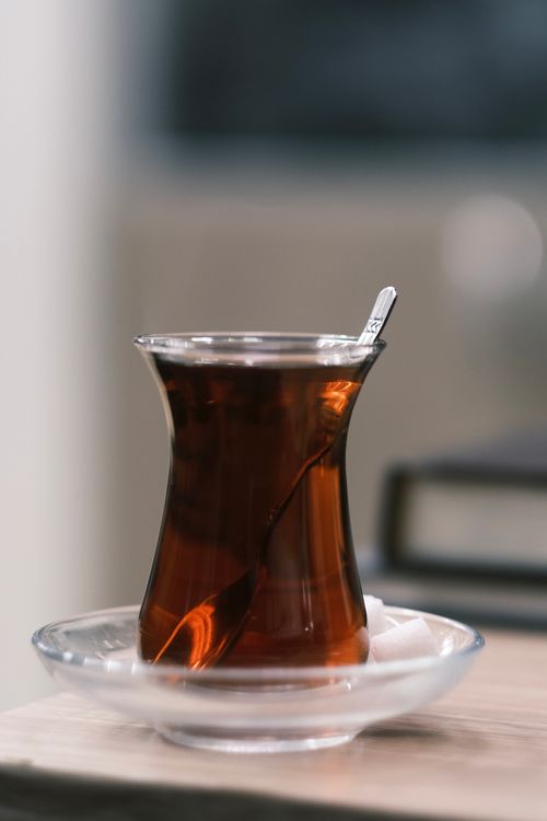Free A close-up image of traditional Turkish tea in a glass cup on a clear saucer with a spoon. Stock Photo