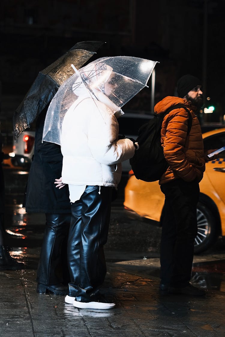 A Group Of Men Standing On The Street At Night