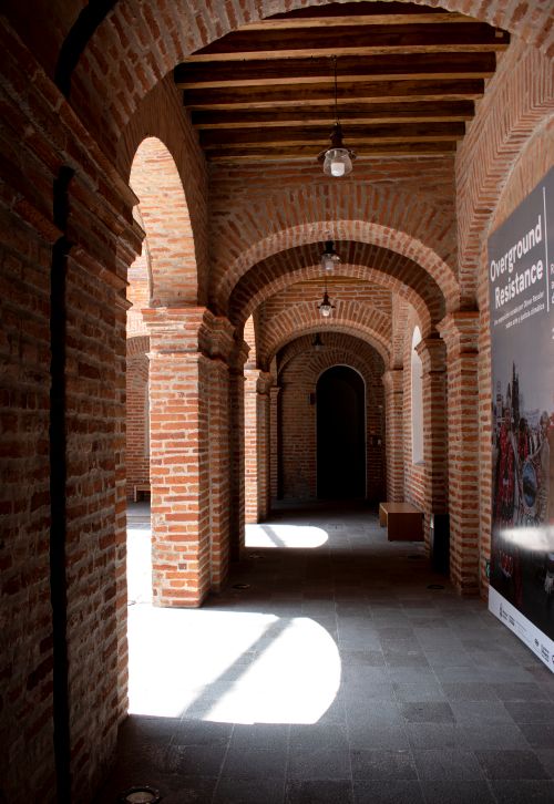 Free Sunlit brick archway with vintage lamps in Quito, capturing historic architecture. Stock Photo
