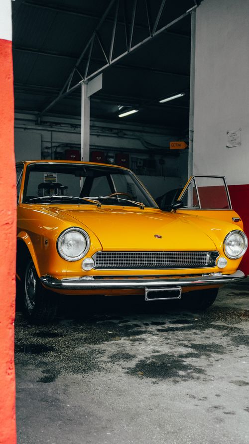 Free Classic yellow car parked in a garage in Naples, Italy, exuding nostalgia. Stock Photo