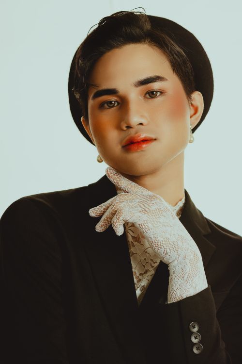 Free A stylish portrait of a person in a suit with a hat and lace glove, against a plain background. Stock Photo