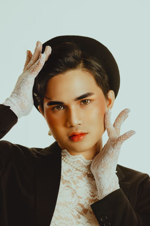 Free Striking studio portrait featuring a person in elegant attire with lace gloves, hat, and makeup. Stock Photo