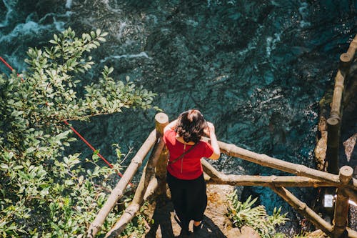 Woman Standing on Balcony While Watching Body of Water