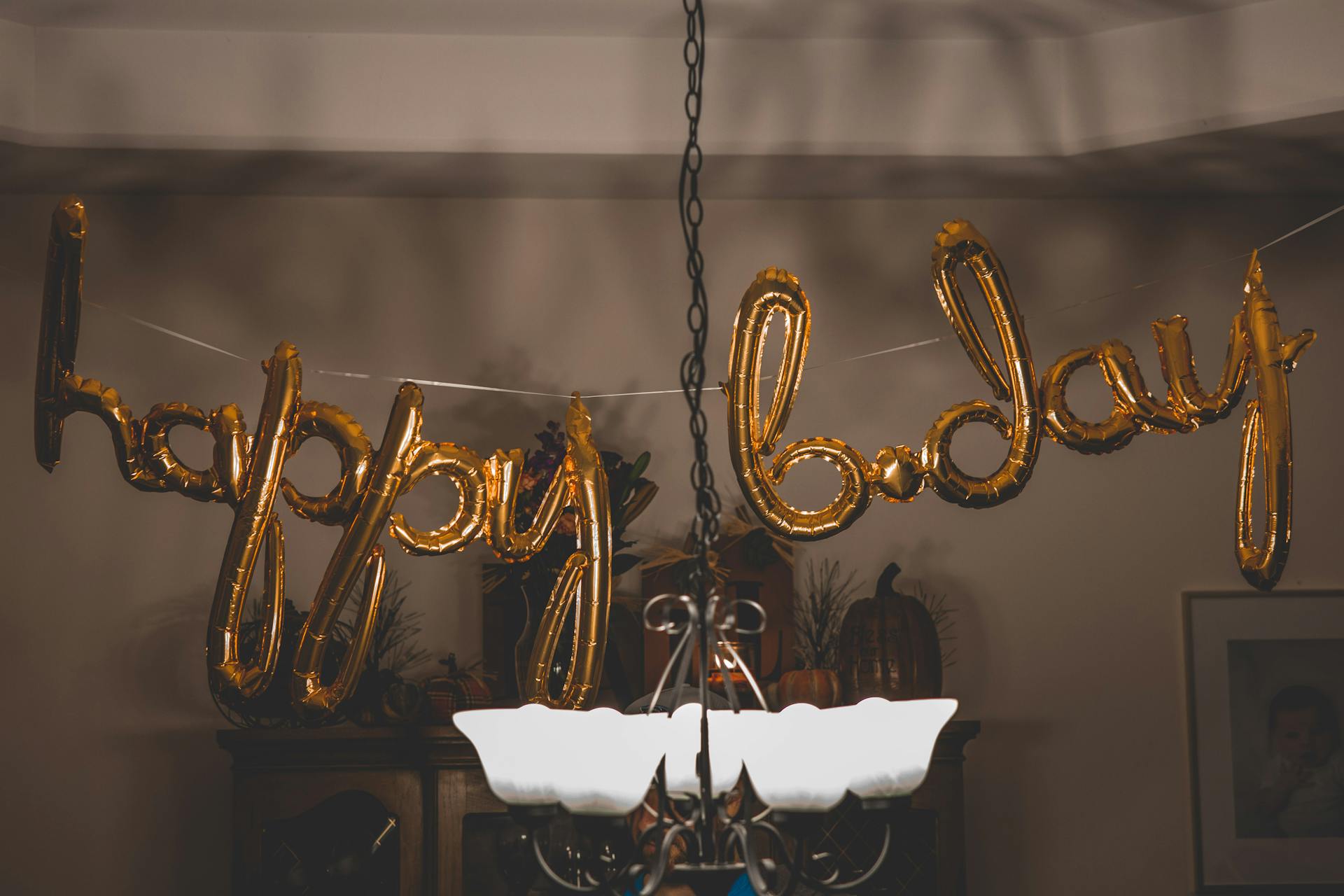 Festive gold balloons spelling happy birthday hanging indoors for party themes