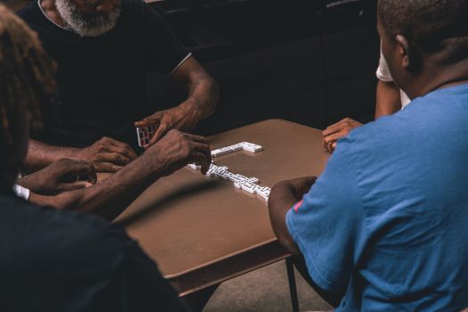 A group of senior men playing dominoes on a table indoors, engaging in recreation and strategy.