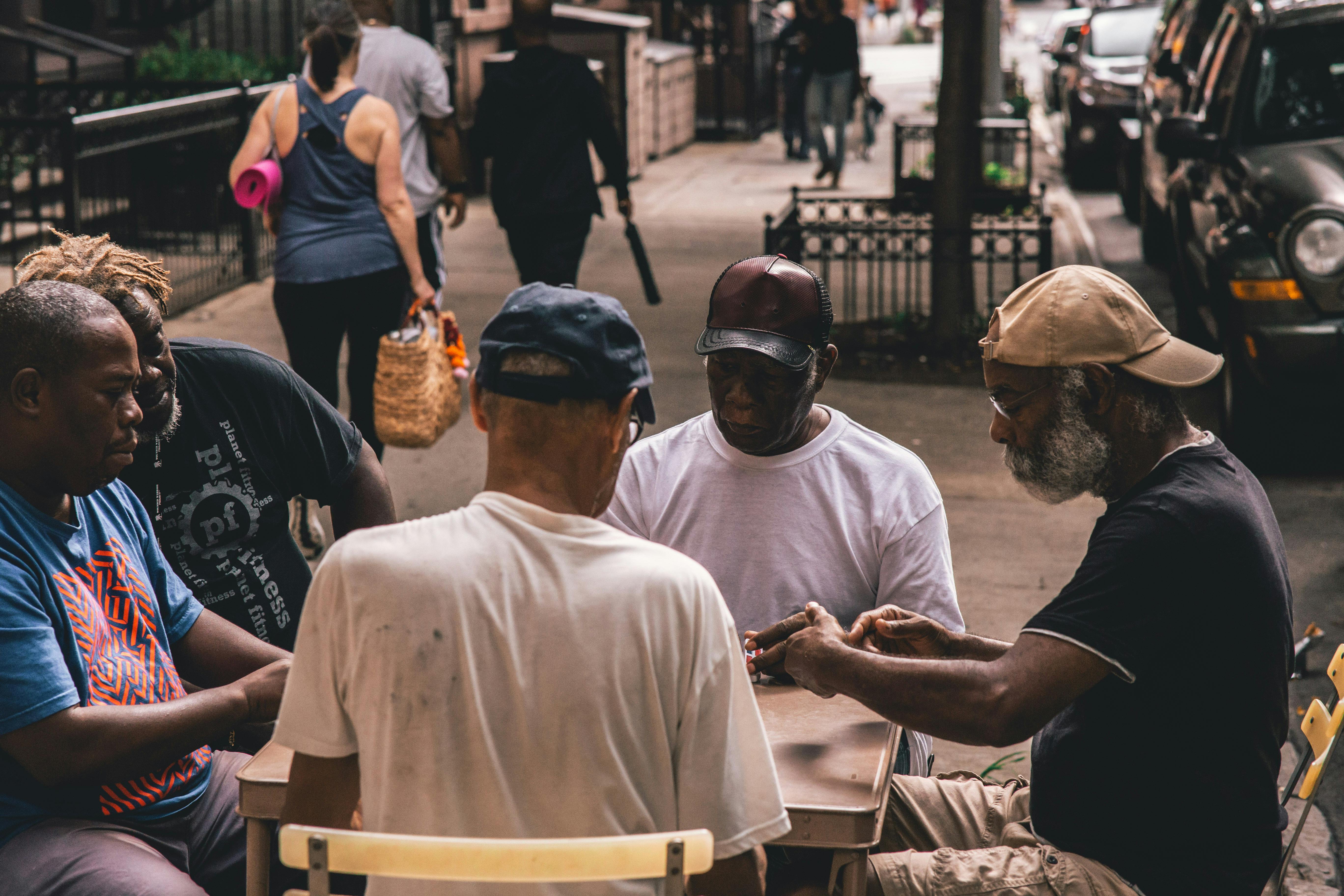 men sitting beside table on pathway near people walking beside rail