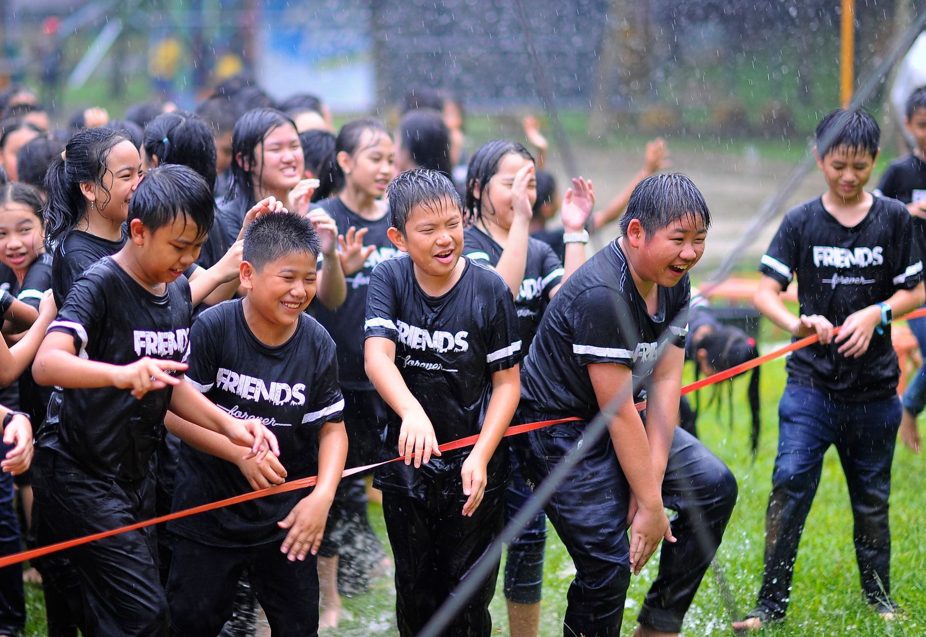 Group of wet and happy children enjoying rain during outdoor fun.