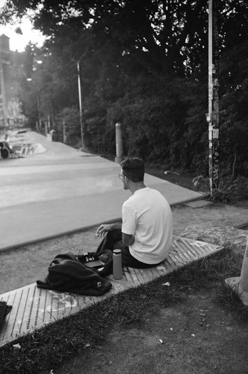 Back View of Man Sitting at Skatepark in Black and White