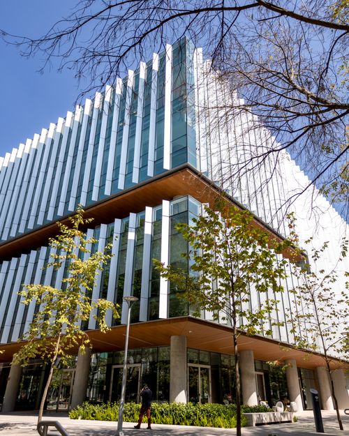 Free Contemporary glass-fronted office building with trees in urban setting on a sunny day. Stock Photo