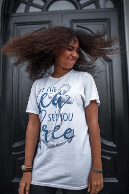 Black woman with curly hair and expressive pose outdoors. Fashion portrait capturing movement and style.