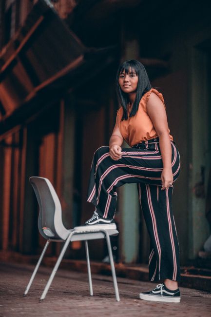 Portrait of a fashionable young woman posing with a chair in an urban setting, Panama.