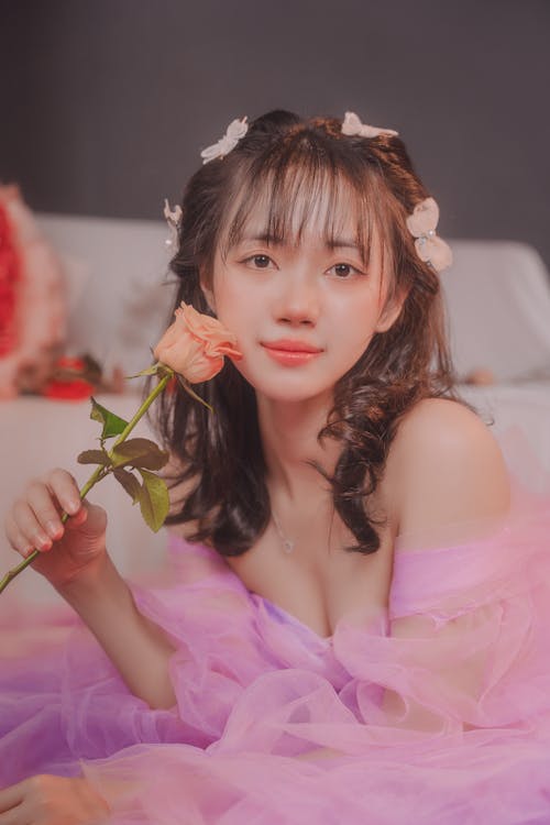 Young Woman Posing in a Pink, Tulle Dress and Holding a Rose 