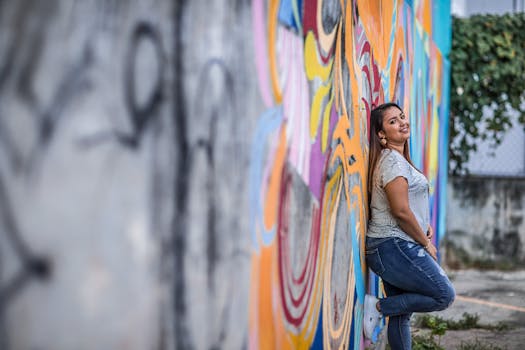 Smiling young woman leans against a vibrant graffiti wall in Panama, showcasing urban street style.