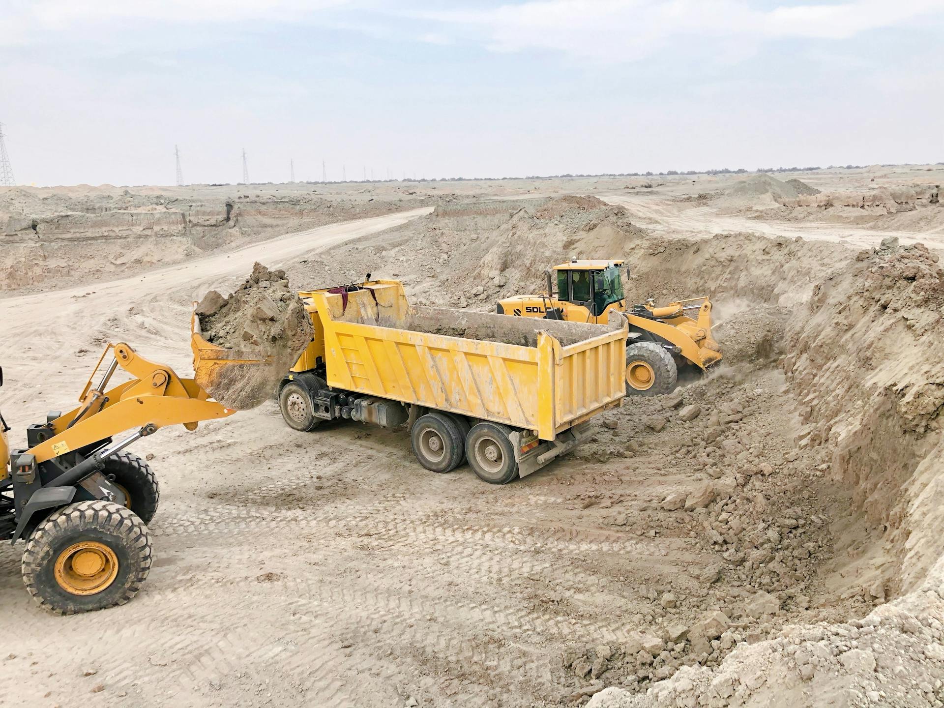 Excavators and trucks at a construction site moving earth for land development.