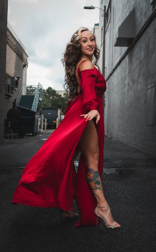 Young Woman in a Red Dress and Heels Posing on a Street in City 