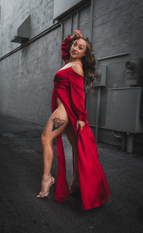 Young Woman in a Red Dress and Heels Posing on a Street in City 