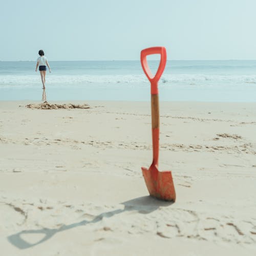 An Orange Shovel on Brown Sand
