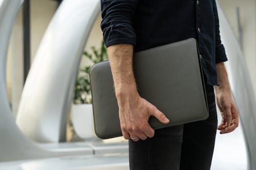 Close-up of a Man Holding a Leather Case with a Laptop 