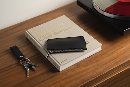 Keys with a Leather Key Chain and a Leather Case Lying on a Book on a Dresser 