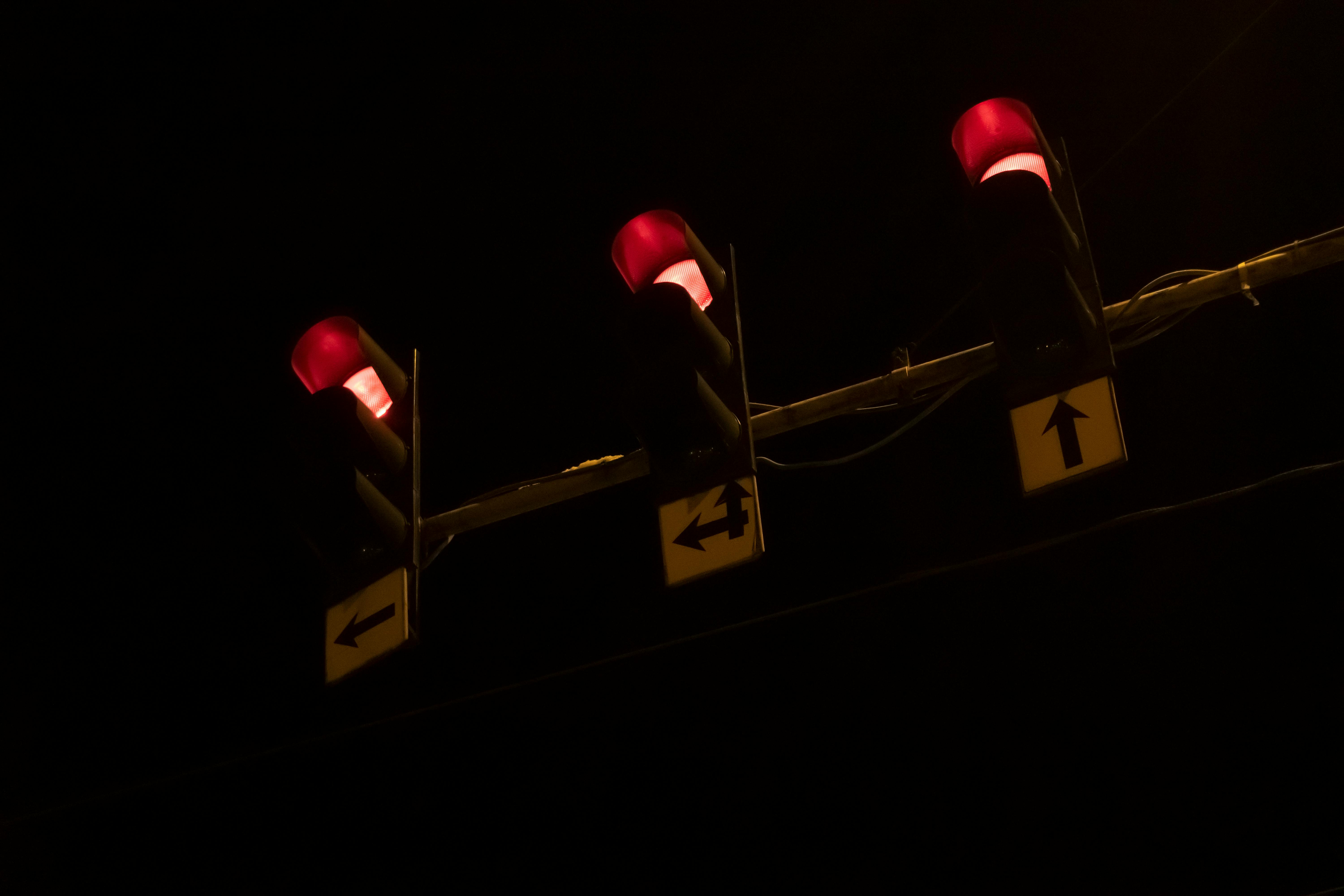 無料 暗い夜空を背景に3つの赤い信号が明るく輝き、鮮やかなコントラストを生み出しています。 写真素材