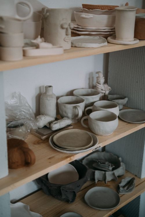 Free A collection of handcrafted pottery items on wooden shelves in a studio setting. Stock Photo