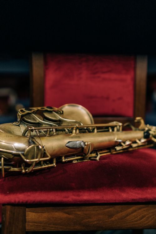 Free Detailed view of a saxophone resting on a red velvet chair in an orchestra setting. Stock Photo
