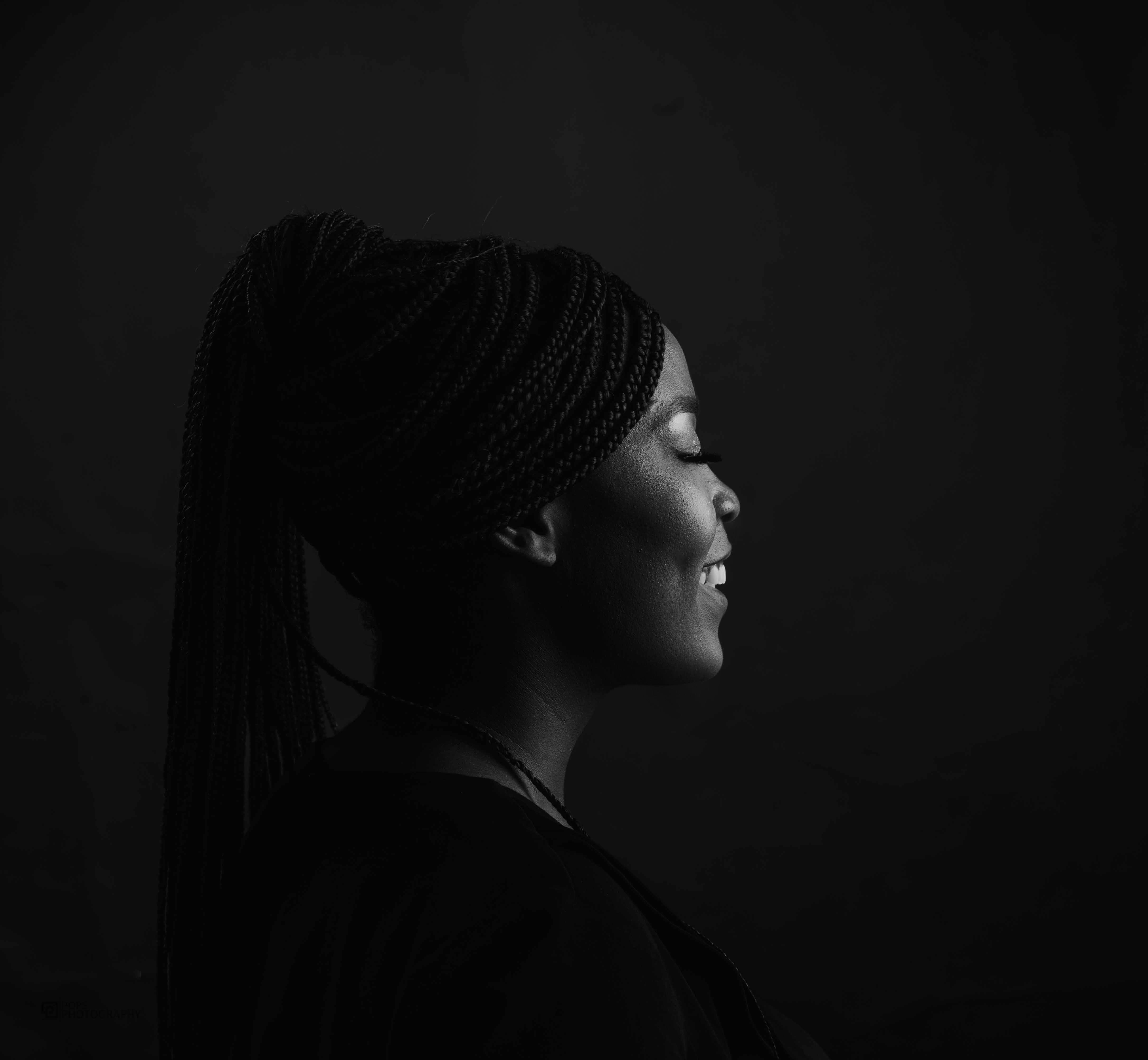 Elegant black and white portrait of a smiling woman with braided hair in profile view.