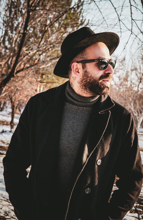 Free Man in a black coat and fedora enjoying a sunny winter day outdoors. Stock Photo