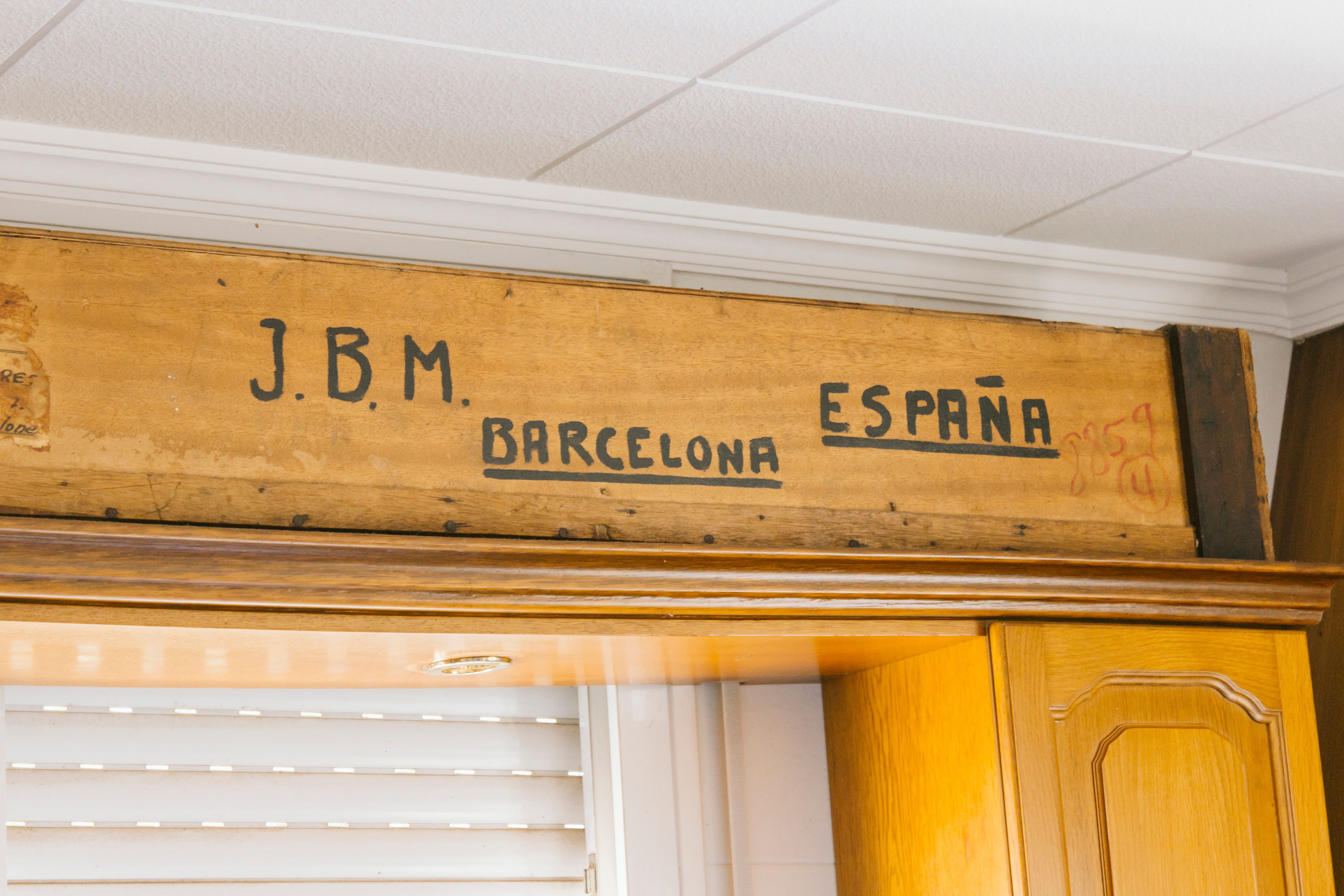 Wooden sign displaying Barcelona and España text, indoors.