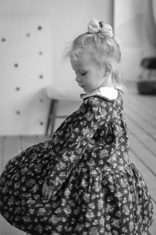 Free Delightful black and white portrait of a girl in a floral dress, exuding innocence. Stock Photo