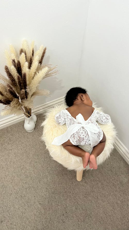 Baby Girl Lying Down on Chair in Corner