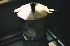 A classic moka pot brewing coffee on a stove, capturing a cozy kitchen scene.