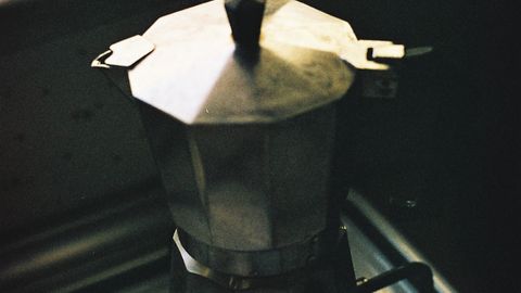 A classic moka pot brewing coffee on a stove, capturing a cozy kitchen scene.