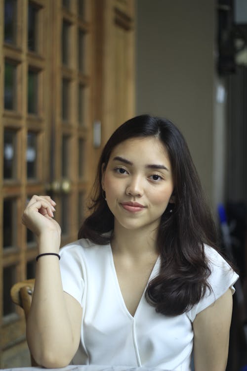 Young Woman in a White Blouse Sitting at a Table