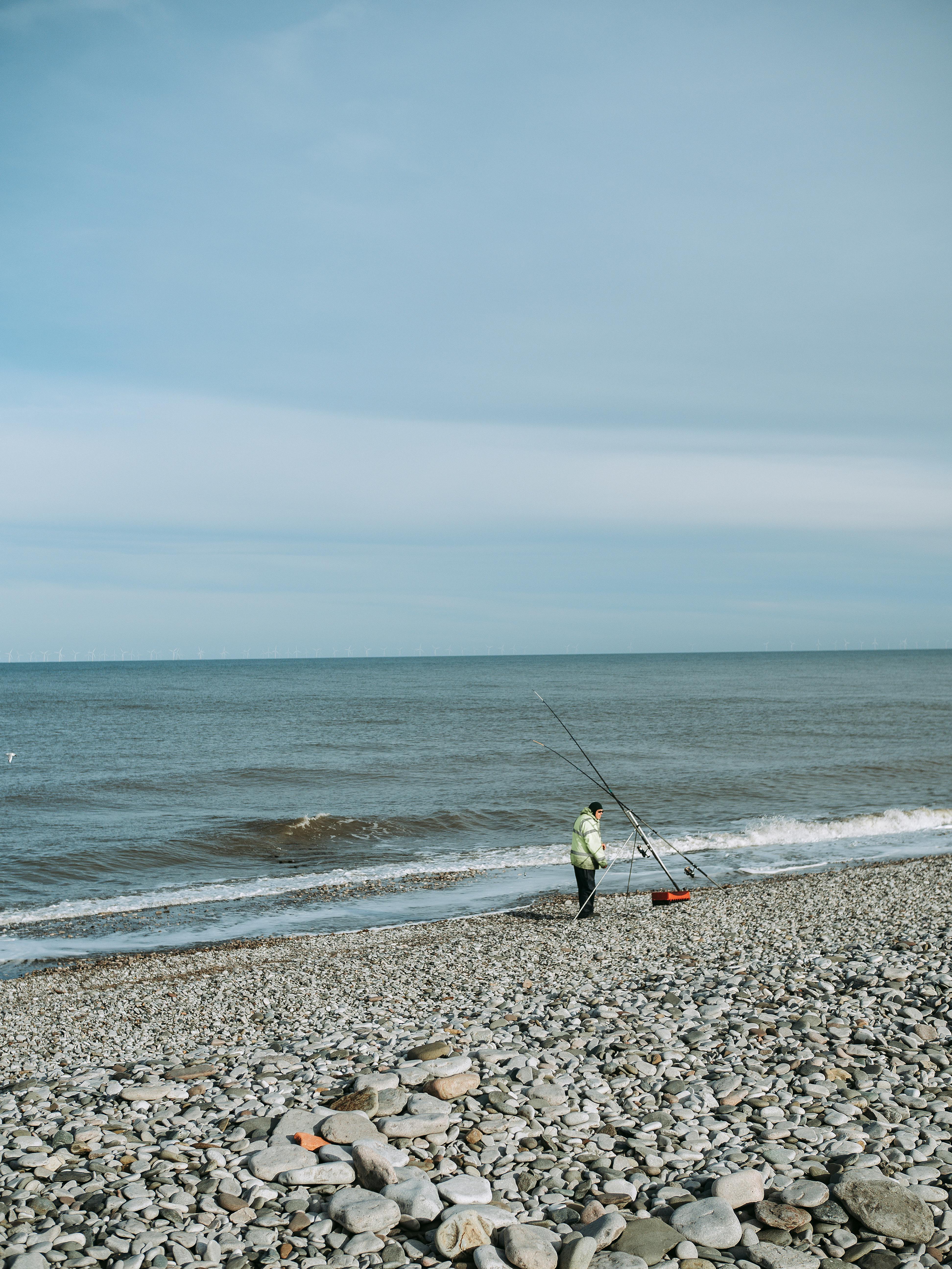 man fishing on a rock beach