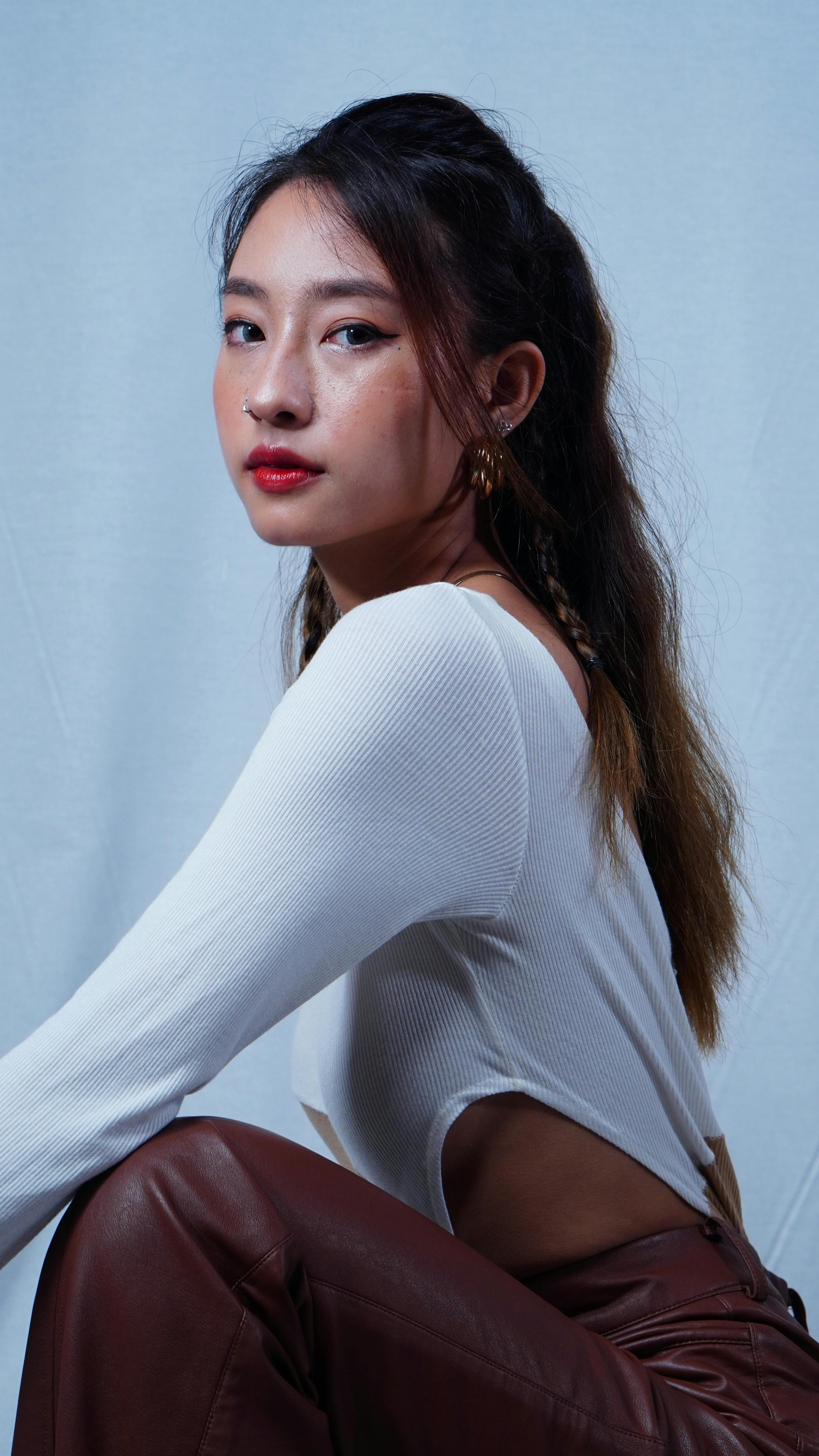 Stylish portrait of a confident woman posing against a white backdrop, showcasing modern fashion.