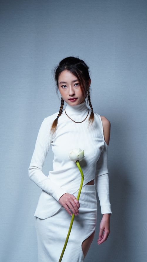 Free Fashion portrait of a woman in white with braided hair holding a white flower, against a soft background. Stock Photo