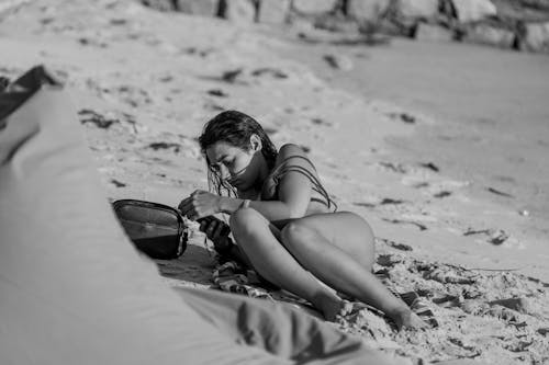 Free A Grayscale Photo of a Woman Lying on the Beach Sand Stock Photo