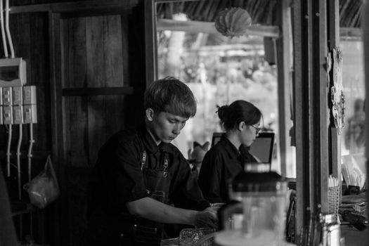 Black and white photo of two baristas working in a cozy cafe environment.