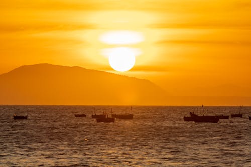 Бесплатное стоковое фото с закат, лодки, море