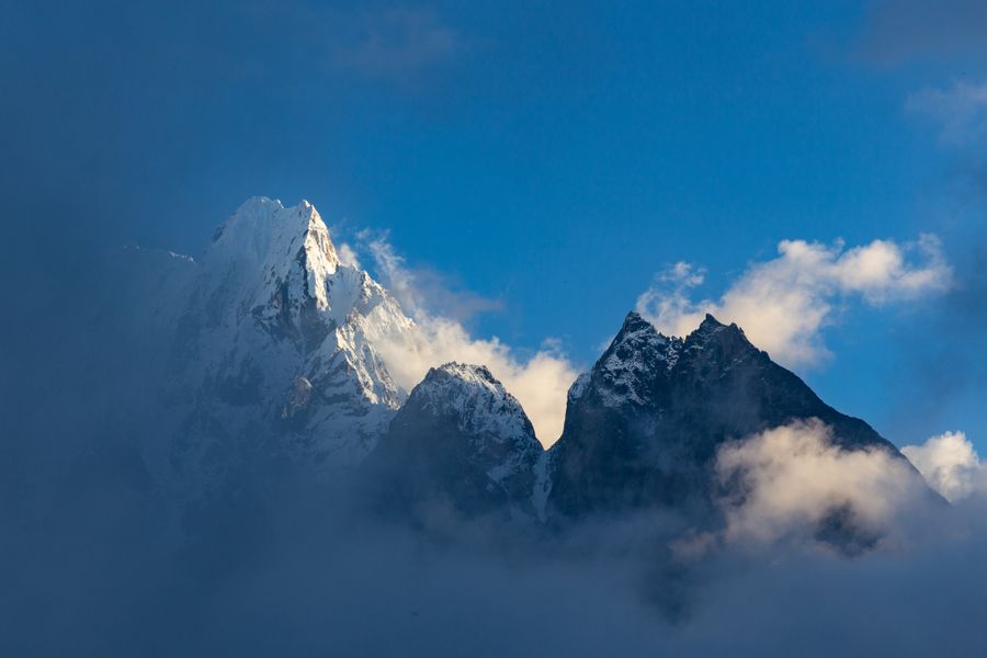 Majestic snowcapped peaks of the Himalayas rise above the clouds in a dramatic landscape view.