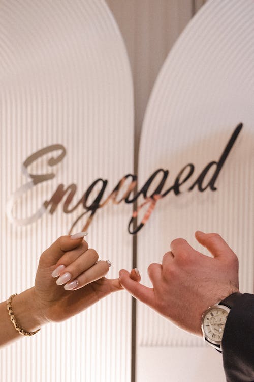 Close-up of Engaged Couple Holding Fingers Showing Unity