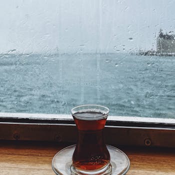 Turkish tea glass on a rainy windowsill with sea view evokes cozy vibes.