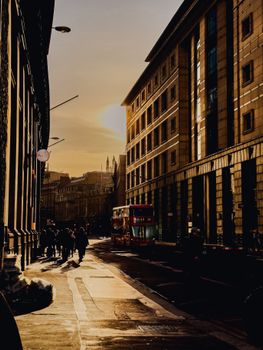 Silhouettes of people walking city streets at sunset, featuring London's iconic double-decker bus.